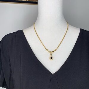 Gold tone necklace with black and white gemstone pendant